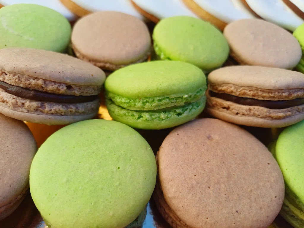 Macarons chocolat et pistache sur fond blanc avec en arrière blanc les macarons