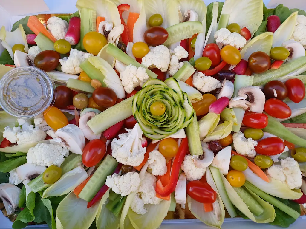 Plateau de crudités avec fleur de courgette et autre légumes en fond fait par Océane Pâtisserie & Brunch